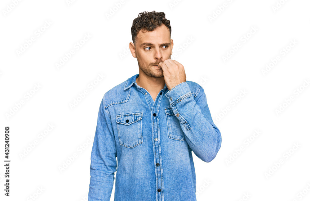 Young hispanic man wearing casual denim jacket looking stressed and nervous with hands on mouth biting nails. anxiety problem. Young hispanic man wearing casual denim jacket looking stressed and nervous with hands on mouth biting nails. anxiety problem.