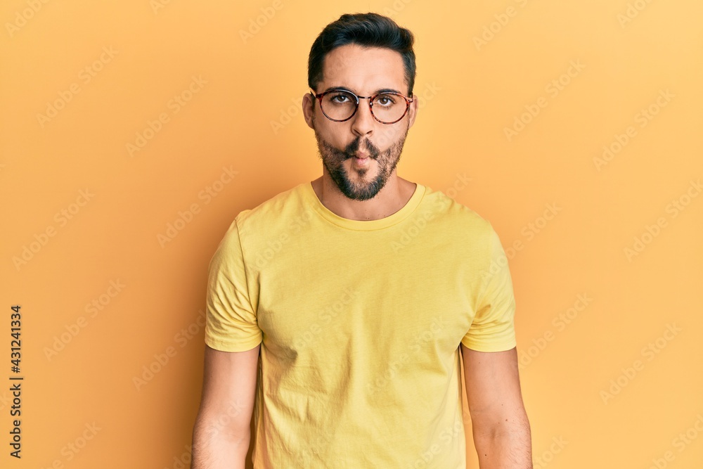 Young hispanic man wearing casual clothes and glasses making fish face with lips, crazy and comical gesture. funny expression. Young hispanic man wearing casual clothes and glasses making fish face with lips, crazy and comical gesture. funny expression.