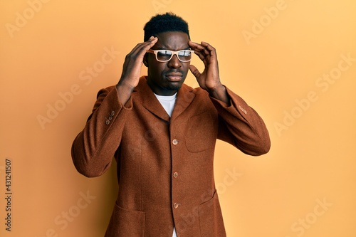 Handsome black man wearing elegant clothes and glasses with hand on head, headache because stress. suffering migraine.