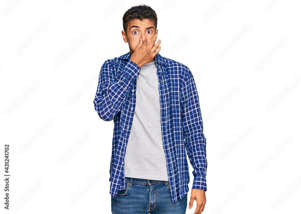 Fototapeta premium Young handsome african american man wearing casual clothes smelling something stinky and disgusting, intolerable smell, holding breath with fingers on nose. bad smell