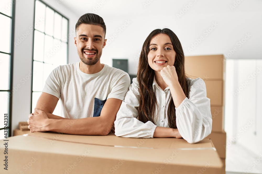 Young hispanic couple smiling happy leaning on cardboard at new home. Young hispanic couple smiling happy leaning on cardboard at new home.