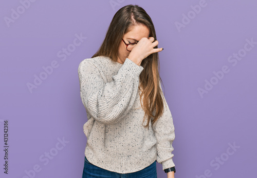 Young blonde woman wearing casual sweater and glasses tired rubbing nose and eyes feeling fatigue and headache. stress and frustration concept. © Krakenimages.com