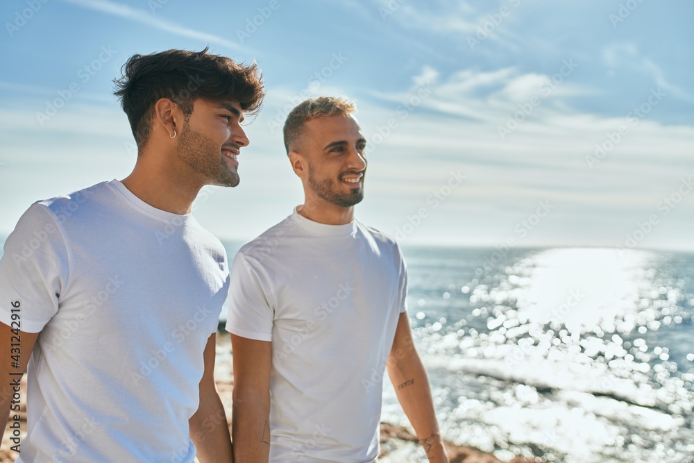 Young gay couple smiling happy walking at the beach promenade. Young gay couple smiling happy walking at the beach promenade.