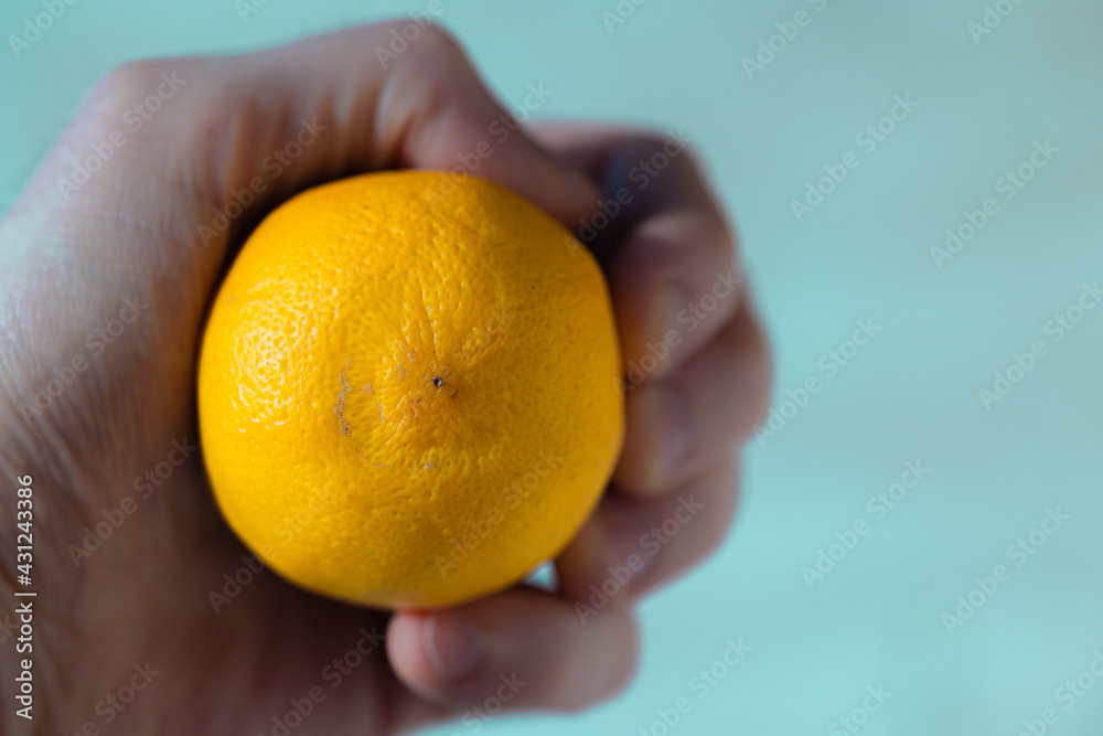 Lemon in hand on a gentle blue background. Compressed citrus in the palm of your hand Lemon in hand on a gentle blue background. Compressed citrus in the palm of your hand