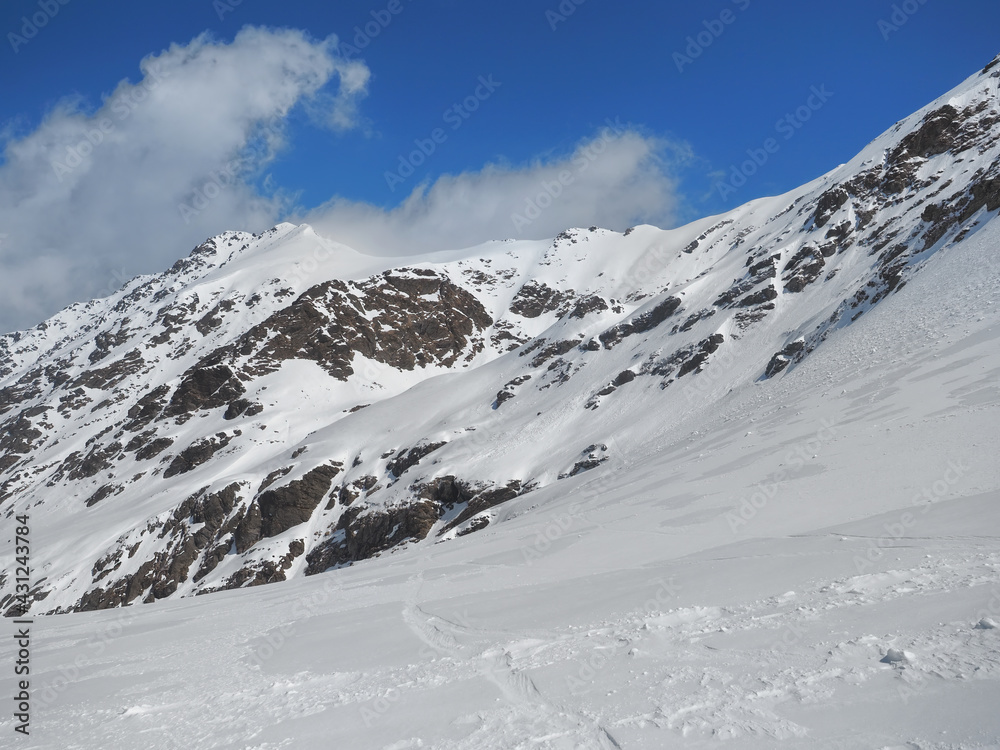 Winter in the rocky mountains covered with snow against blue sky with small clouds