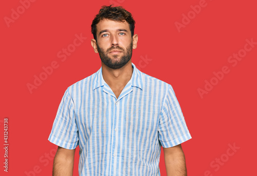 Handsome young man with beard wearing casual fresh shirt relaxed with serious expression on face. simple and natural looking at the camera.