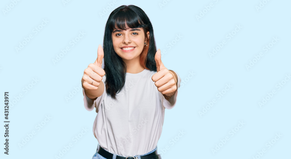 Young hispanic girl wearing casual clothes approving doing positive gesture with hand, thumbs up smiling and happy for success. winner gesture. Young hispanic girl wearing casual clothes approving doing positive gesture with hand, thumbs up smiling and happy for success. winner gesture.