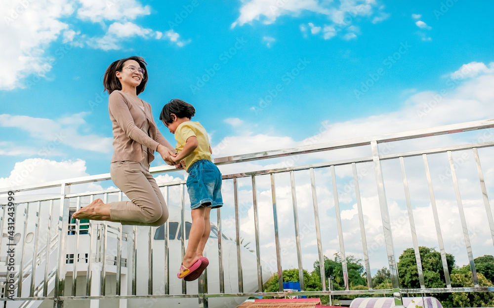 Asian woman mother with little child girl jumping with a plane and blue sky background, happy family relaxes time concept Asian woman mother with little child girl jumping with a plane and blue sky background, happy family relaxes time concept