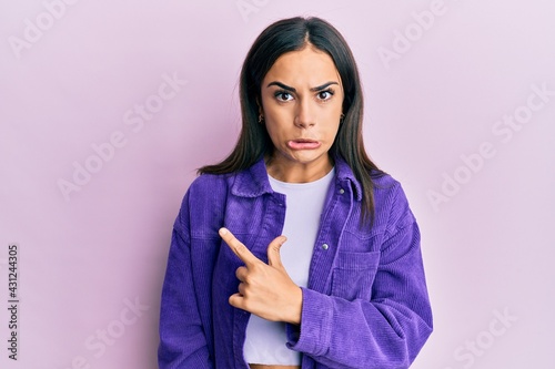 Young brunette woman wearing casual clothes pointing aside worried and nervous with forefinger, concerned and surprised expression