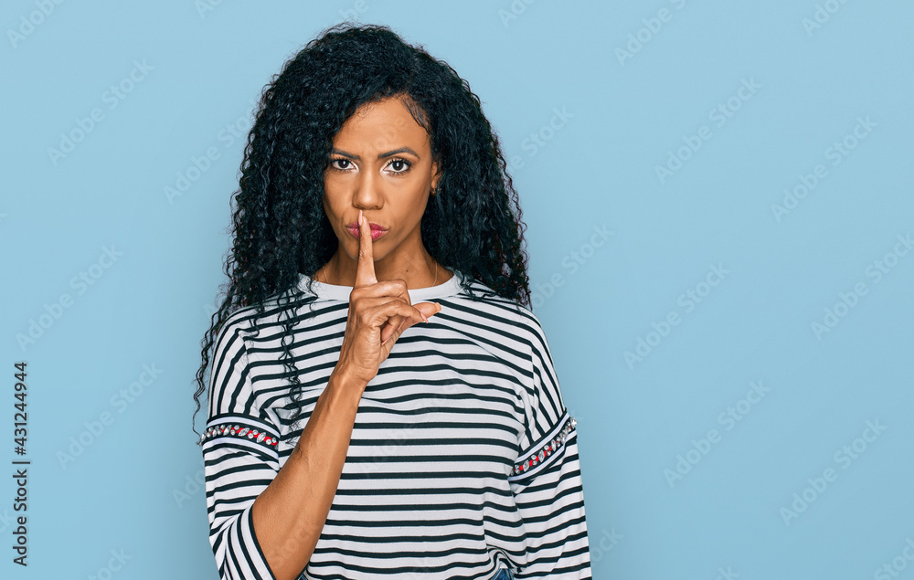 Middle age african american woman wearing casual clothes asking to be quiet with finger on lips. silence and secret concept. Middle age african american woman wearing casual clothes asking to be quiet with finger on lips. silence and secret concept.