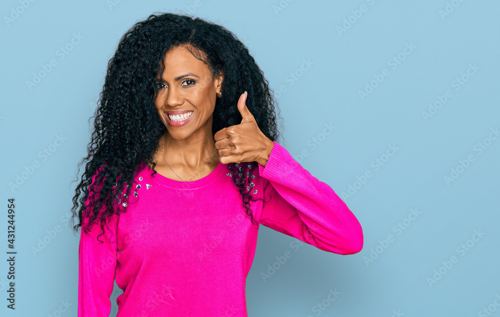 Middle age african american woman wearing casual clothes doing happy thumbs up gesture with hand. approving expression looking at the camera showing success.