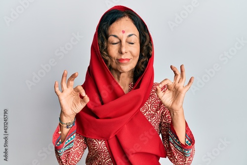 Middle age hispanic woman wearing tradition sherwani saree clothes relax and smiling with eyes closed doing meditation gesture with fingers. yoga concept.