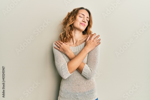 Young caucasian woman wearing casual clothes hugging oneself happy and positive, smiling confident. self love and self care