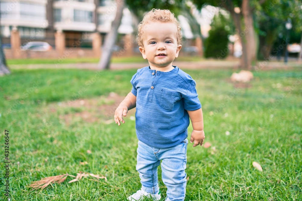 Cute and happy little boy having fun at the park on a sunny day. Beautiful blonde hair male toddler playing outdoors Cute and happy little boy having fun at the park on a sunny day. Beautiful blonde hair male toddler playing outdoors