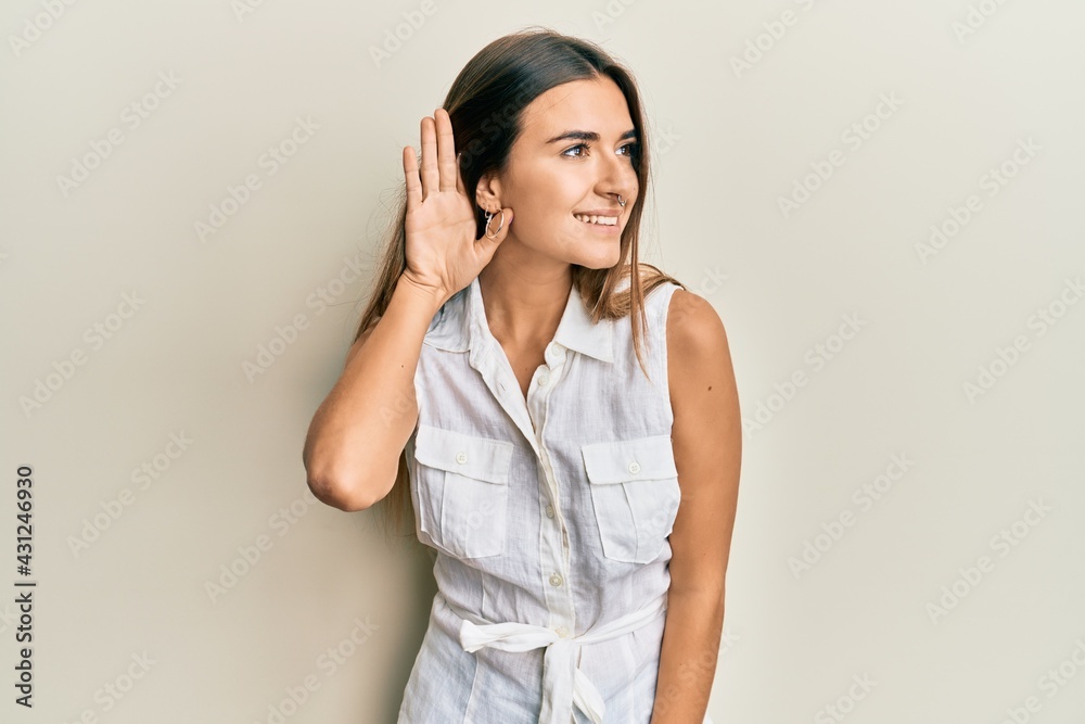 Young hispanic woman wearing casual clothes smiling with hand over ear listening and hearing to rumor or gossip. deafness concept. Young hispanic woman wearing casual clothes smiling with hand over ear listening and hearing to rumor or gossip. deafness concept.