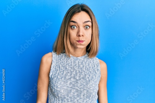 Young caucasian blonde woman wearing casual t shirt puffing cheeks with funny face. mouth inflated with air, crazy expression. © Krakenimages.com
