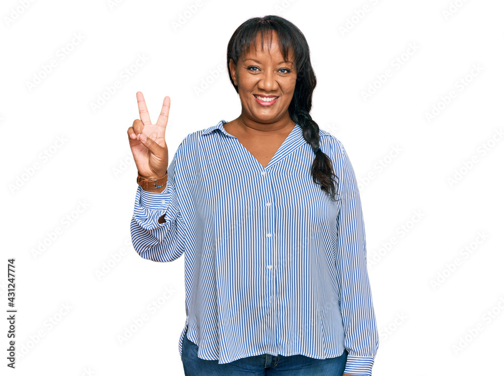 Hispanic middle age woman wearing casual clothes smiling with happy face winking at the camera doing victory sign. number two. Hispanic middle age woman wearing casual clothes smiling with happy face winking at the camera doing victory sign. number two.