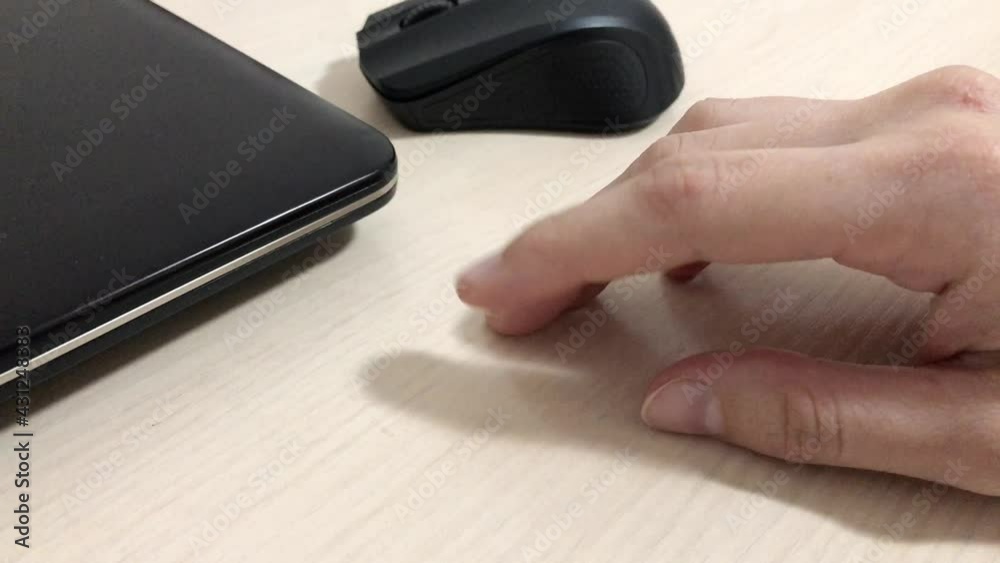 female hand knocks his fingers on the wooden table next to a laptop. female hand knocks his fingers on the wooden table next to a laptop.