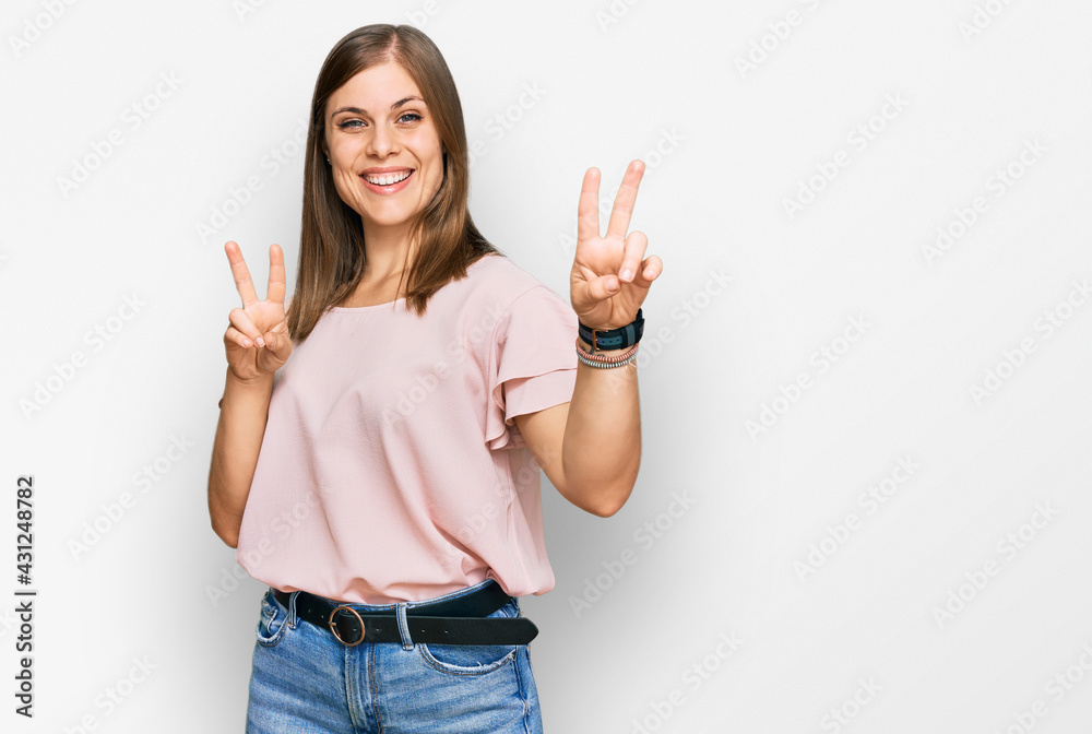 Beautiful caucasian woman wearing casual clothes smiling looking to the camera showing fingers doing victory sign. number two. Beautiful caucasian woman wearing casual clothes smiling looking to the camera showing fingers doing victory sign. number two.