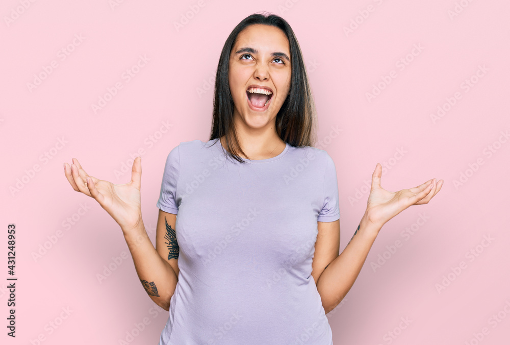 Young hispanic woman wearing casual clothes crazy and mad shouting and yelling with aggressive expression and arms raised. frustration concept. Young hispanic woman wearing casual clothes crazy and mad shouting and yelling with aggressive expression and arms raised. frustration concept.