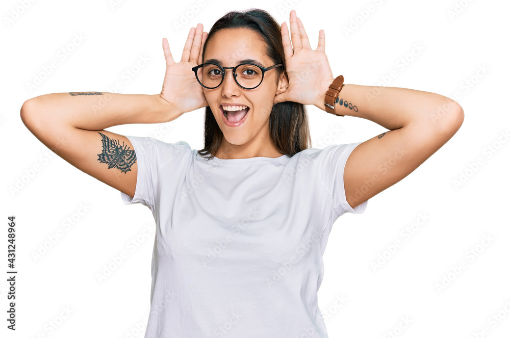 Young hispanic woman wearing casual white t shirt smiling cheerful playing peek a boo with hands showing face. surprised and exited Young hispanic woman wearing casual white t shirt smiling cheerful playing peek a boo with hands showing face. surprised and exited