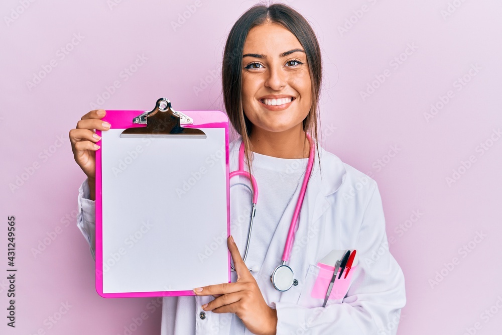 Beautiful hispanic woman wearing doctor stethoscope holding clipboard smiling with a happy and cool smile on face. showing teeth. Beautiful hispanic woman wearing doctor stethoscope holding clipboard smiling with a happy and cool smile on face. showing teeth.