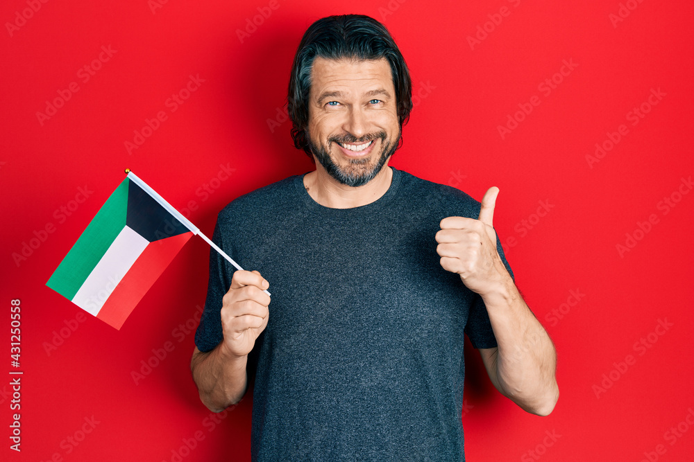 Middle age caucasian man holding kuwait flag smiling happy and positive, thumb up doing excellent and approval sign Middle age caucasian man holding kuwait flag smiling happy and positive, thumb up doing excellent and approval sign