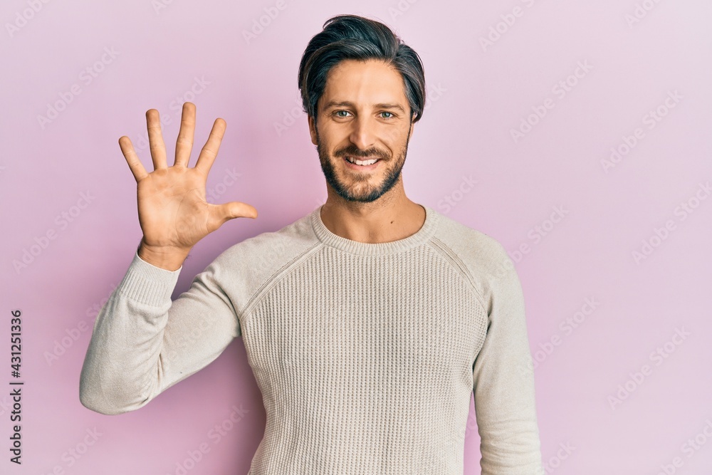 Young hispanic man wearing casual winter sweater showing and pointing up with fingers number five while smiling confident and happy. Young hispanic man wearing casual winter sweater showing and pointing up with fingers number five while smiling confident and happy.