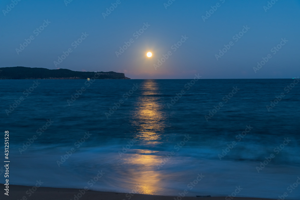 Pink supermoon and full moon rising over the sea