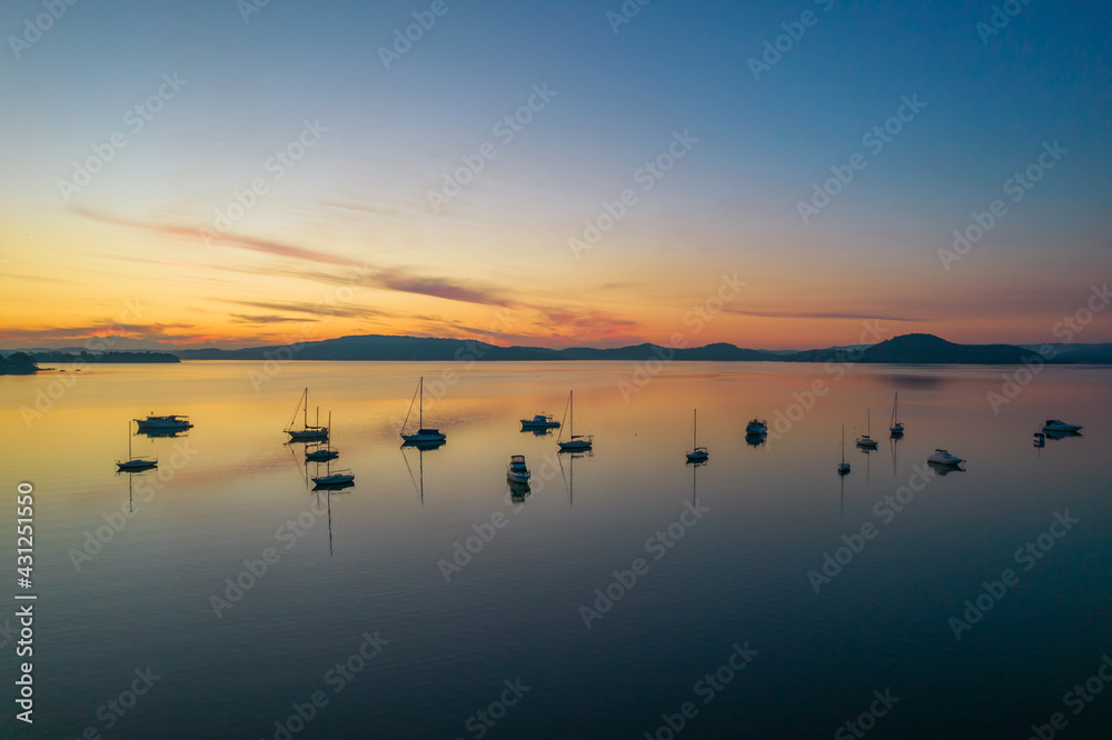 Fototapeta premium Sunrise waterscape with boats, light cloud and reflections