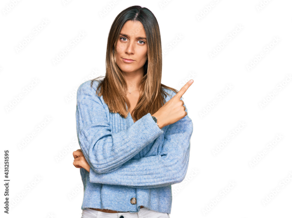 Young woman wearing casual clothes pointing with hand finger to the side showing advertisement, serious and calm face Young woman wearing casual clothes pointing with hand finger to the side showing advertisement, serious and calm face