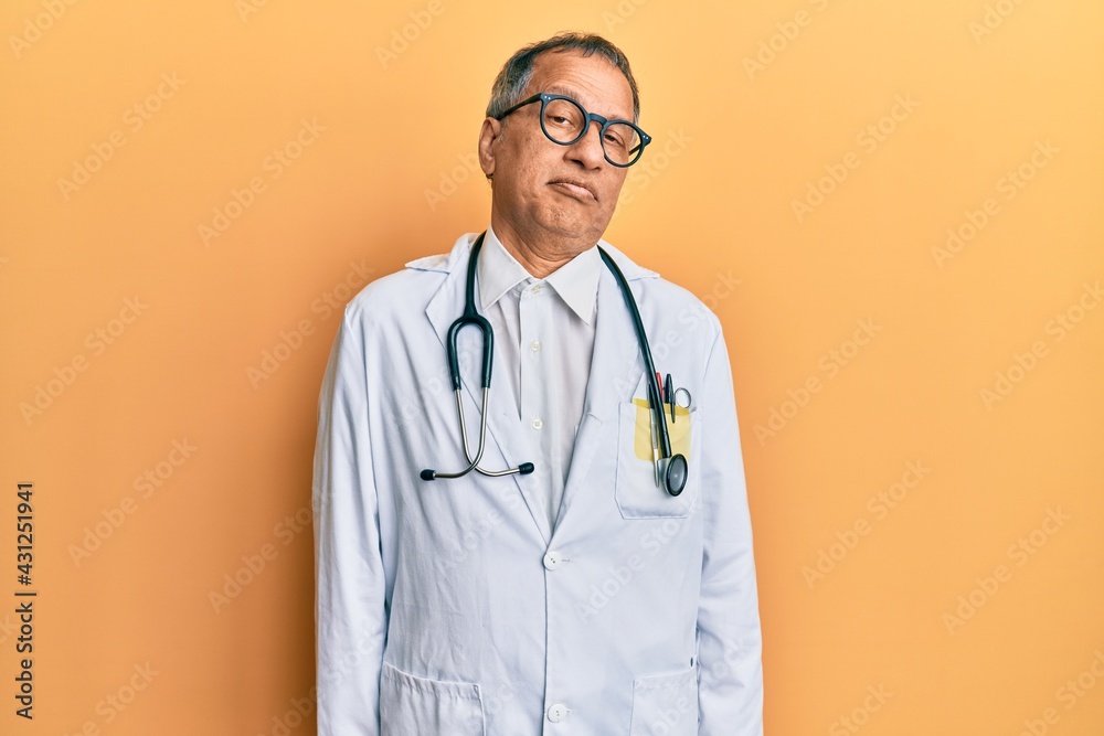 Middle age indian man wearing doctor coat and stethoscope depressed and worry for distress, crying angry and afraid. sad expression.