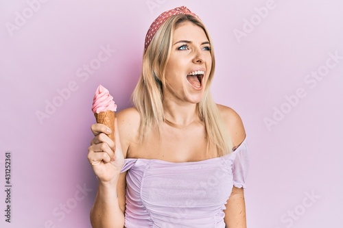 Young caucasian woman holding ice cream angry and mad screaming frustrated and furious, shouting with anger. rage and aggressive concept.