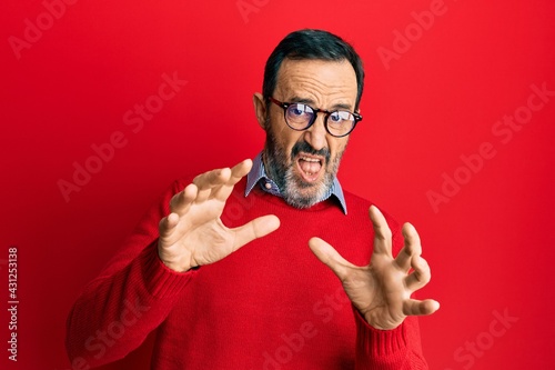 Middle age hispanic man wearing casual clothes and glasses afraid and terrified with fear expression stop gesture with hands, shouting in shock. panic concept.