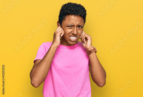 Young african american woman wearing casual clothes covering ears with fingers with annoyed expression for the noise of loud music. deaf concept.