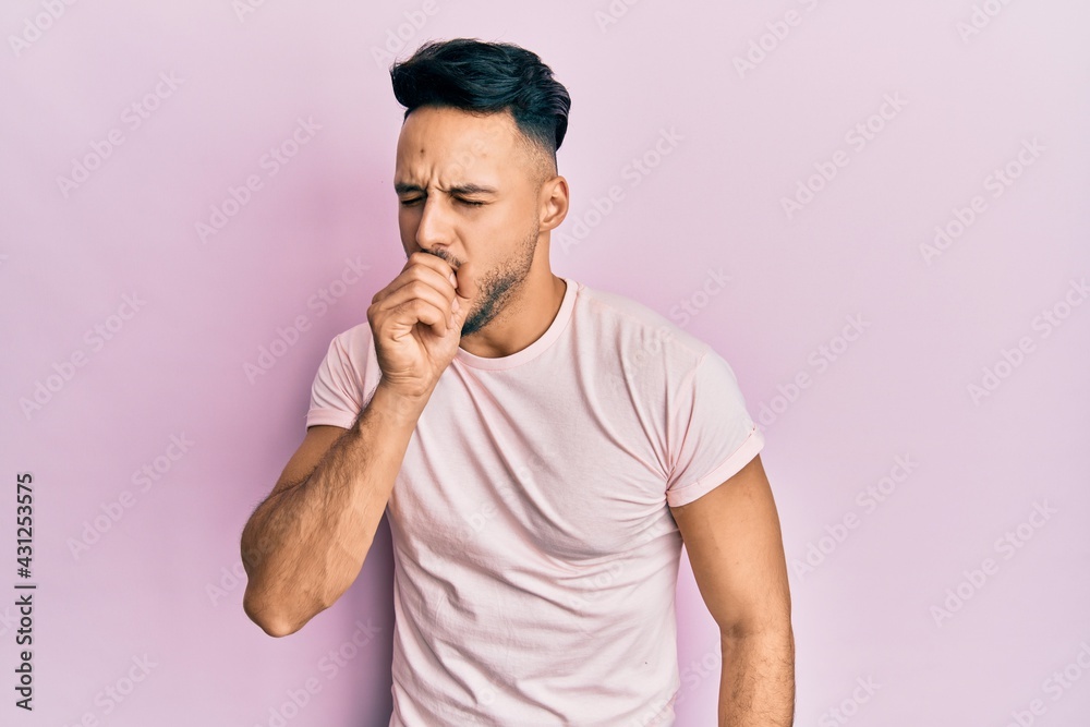 Young arab man wearing casual clothes feeling unwell and coughing as symptom for cold or bronchitis. health care concept. Young arab man wearing casual clothes feeling unwell and coughing as symptom for cold or bronchitis. health care concept.