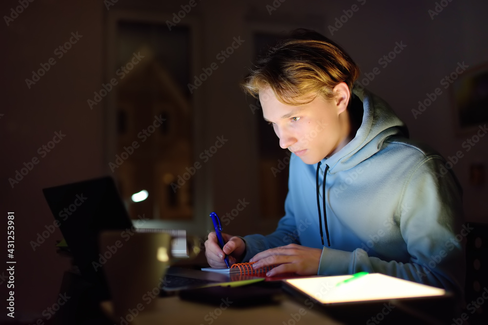 Shocked teenger studying night at home with laptop and tablet pc. Online learning, distance lessons, freelance - modern lifestyle Shocked teenger studying night at home with laptop and tablet pc. Online learning, distance lessons, freelance - modern lifestyle