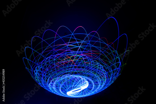 Wonderful and abstract round and parabolic patterns draw different light paths with LED ball lights on a dark background, pendulum.
