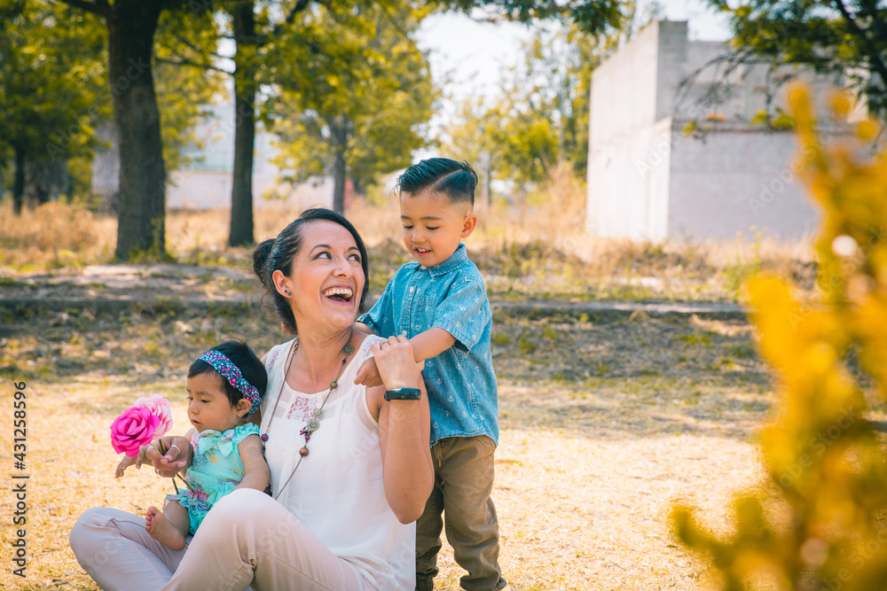 Fototapeta premium Mamá mexicana con sus hijos jugando en un parque felices 