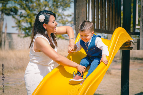 Mamá mexicana con su hijo juegan en una resbaladilla en un parque