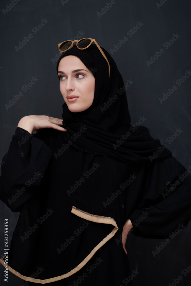 Young muslim in traditional clothes or abaya and sunglasses posing in front of black chalkboard Young muslim in traditional clothes or abaya and sunglasses posing in front of black chalkboard