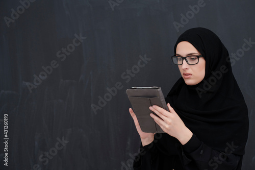 Young Arab businesswoman in traditional clothes or abaya holding tablet computer