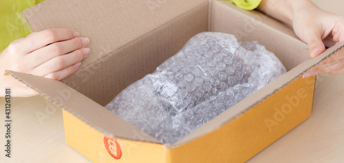 Quadro em tela Closeup hand of woman opening parcel box with check product at home, female unpack with knife, delivery and shipping, shipment and express for shop, online shopping store and service concept