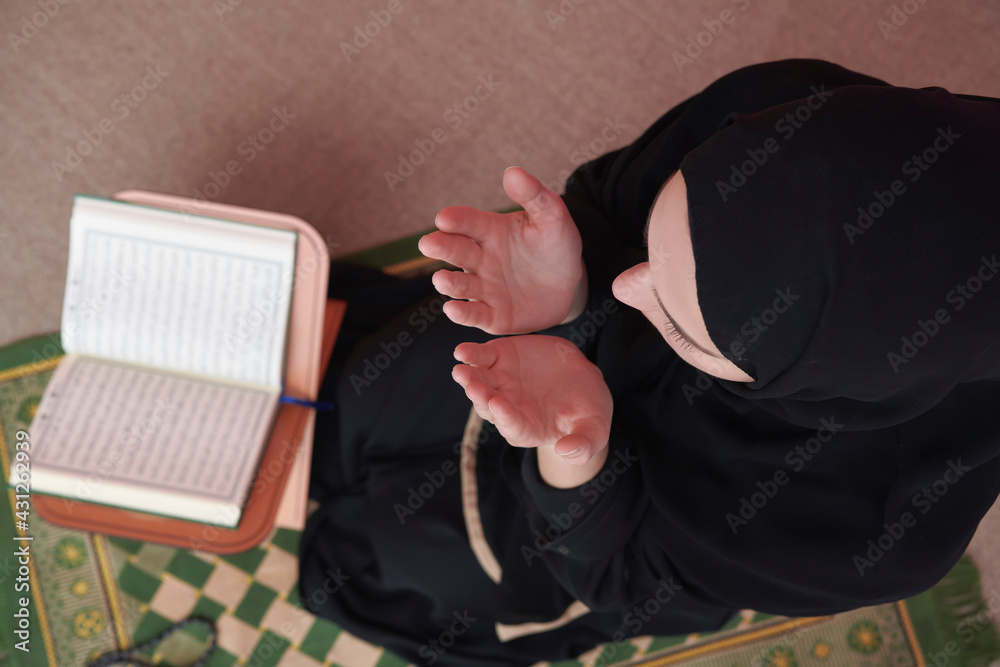 Middle eastern woman praying and reading the holy Quran