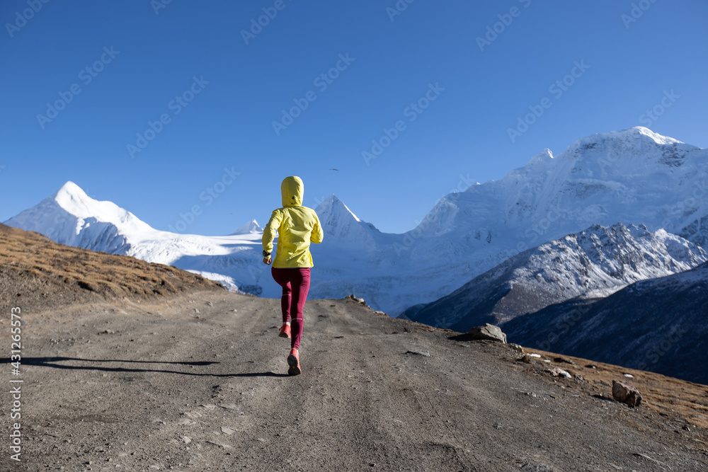 Woman trail runner cross country running in winter mountains