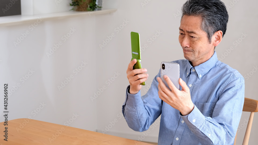 スマホとガラケーを比較するシニア男性 スマホとガラケーを比較するシニア男性