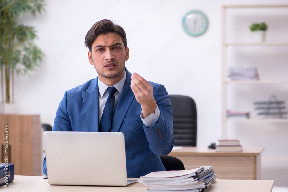 Young male employee being unhappy with excessive work Young male employee being unhappy with excessive work