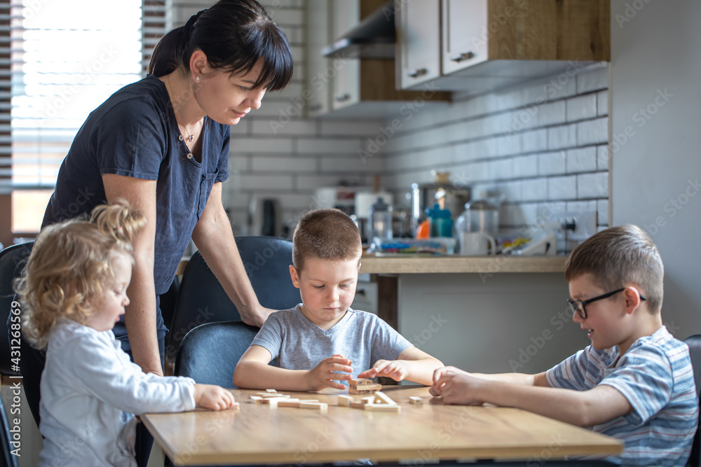 Children with their mother play board at home in the kitchen. Children with their mother play board at home in the kitchen.