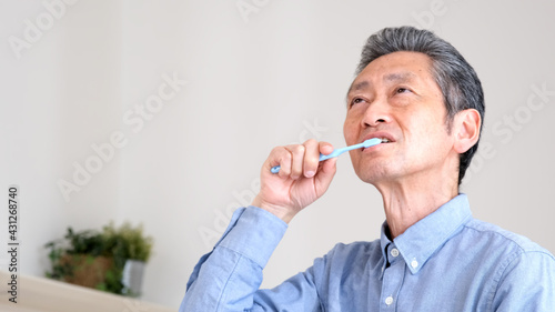 笑顔で歯をブラシで磨くシニア男性