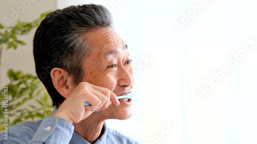 笑顔で歯をブラシで磨くシニア男性